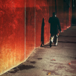 Man-walking-next-to-a-red-wall